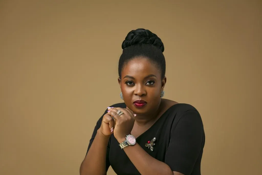 Mabel Adeteye in a black outfit against a warm brown studio backdrop